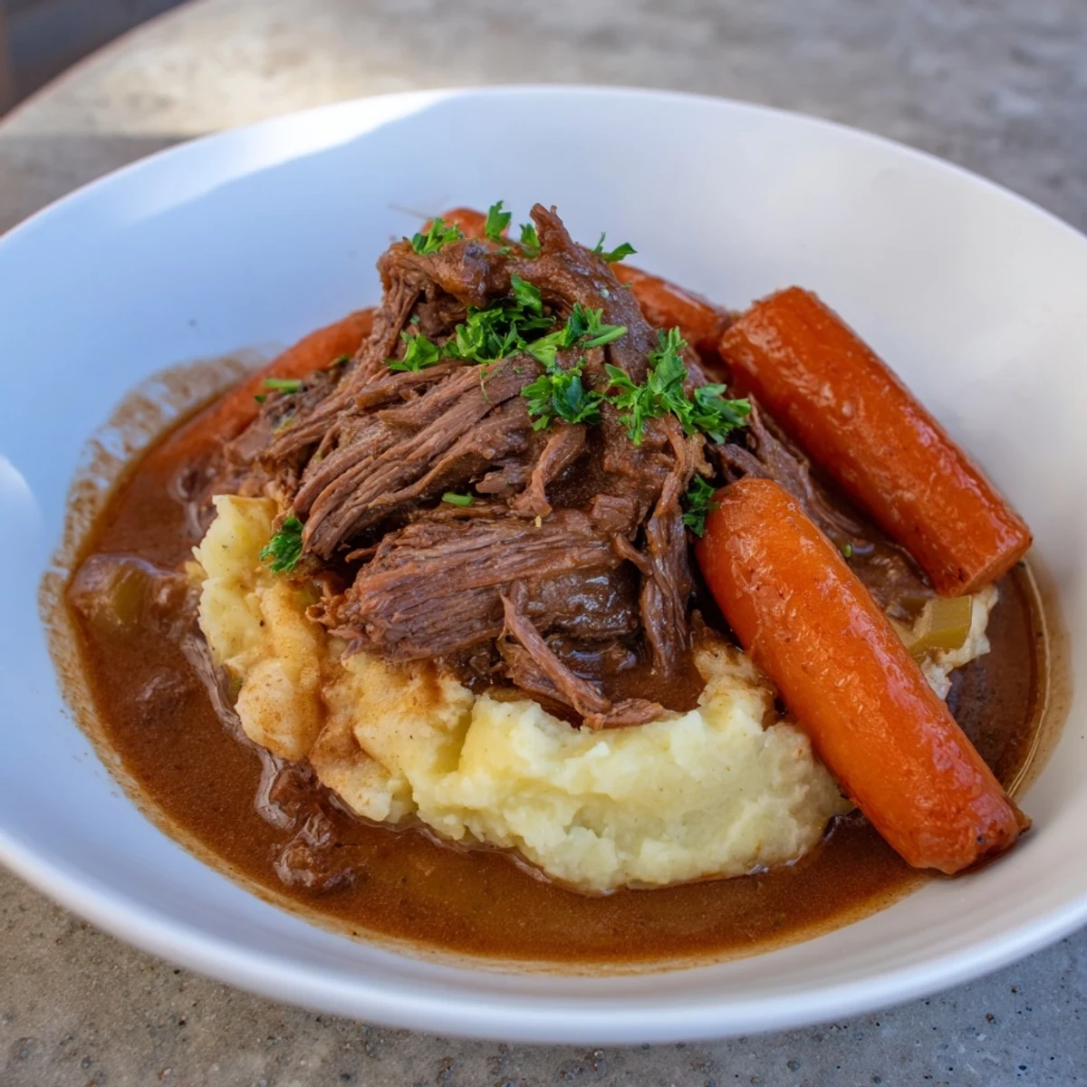 A steaming bowl of comforting slow cooker pot roast with soft mashed potatoes and rich gravy.