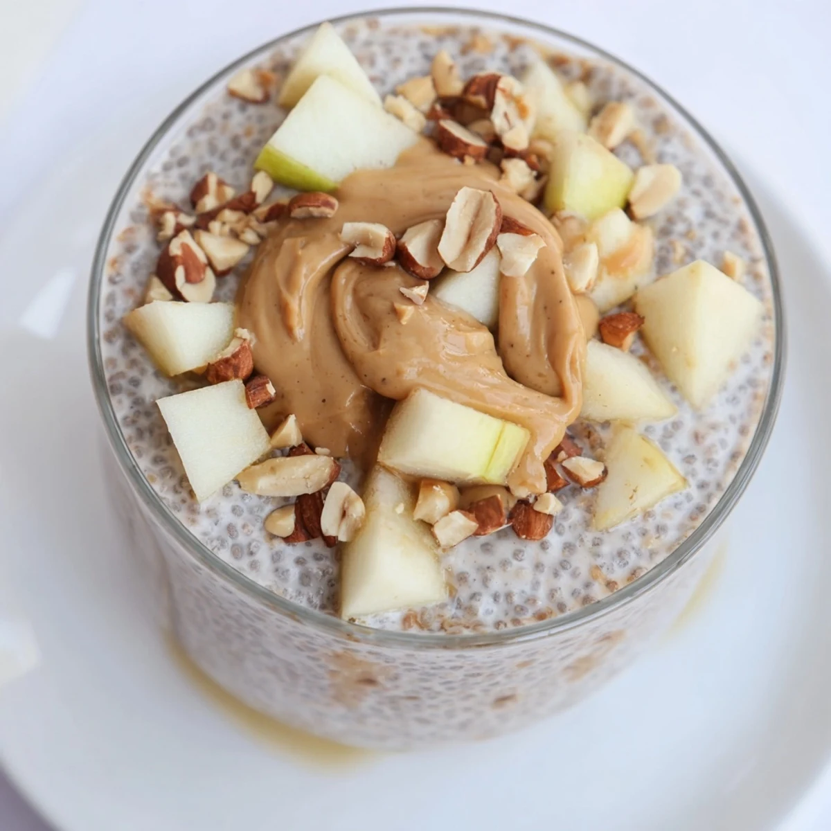 Creamy Apple-Chia Pudding with peanut butter swirled, layered beautifully with apple slices and chopped peanuts, ready to eat.