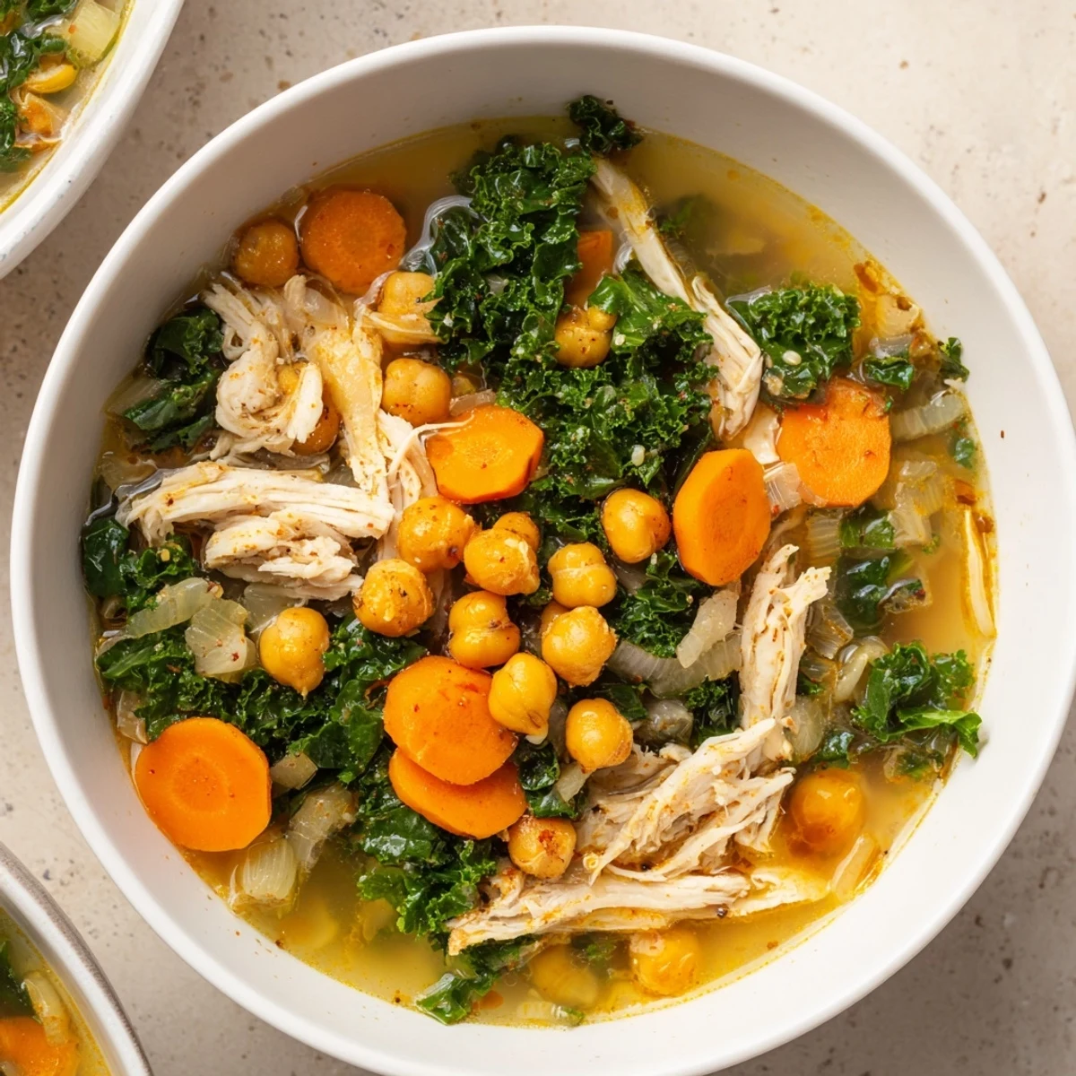 Steaming Chicken Kale Soup with visible bits of shredded chicken and vibrant green kale; a comforting meal.