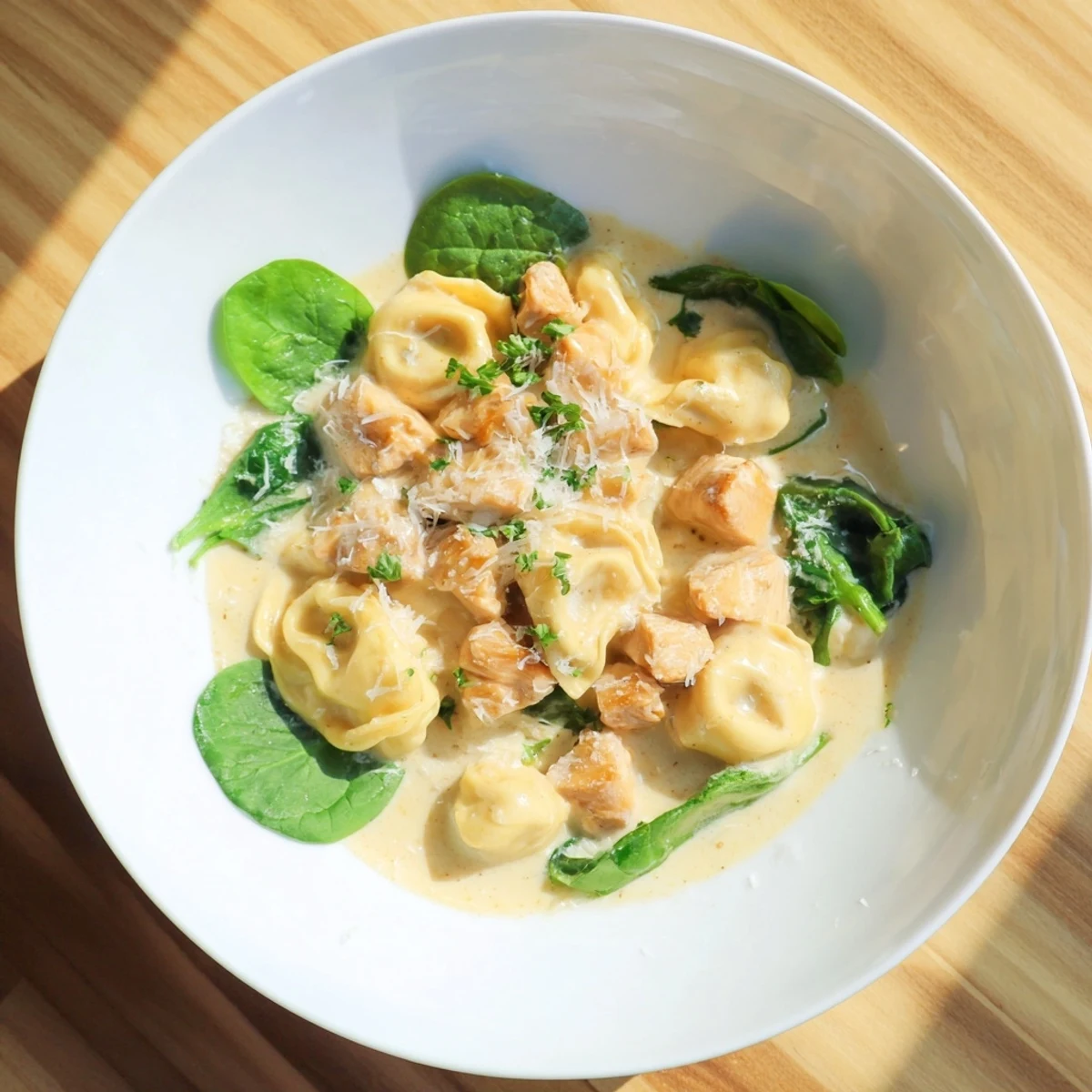 A skillet showcases the finished creamy Chicken and Spinach Tortellini, bubbling with a rich sauce.