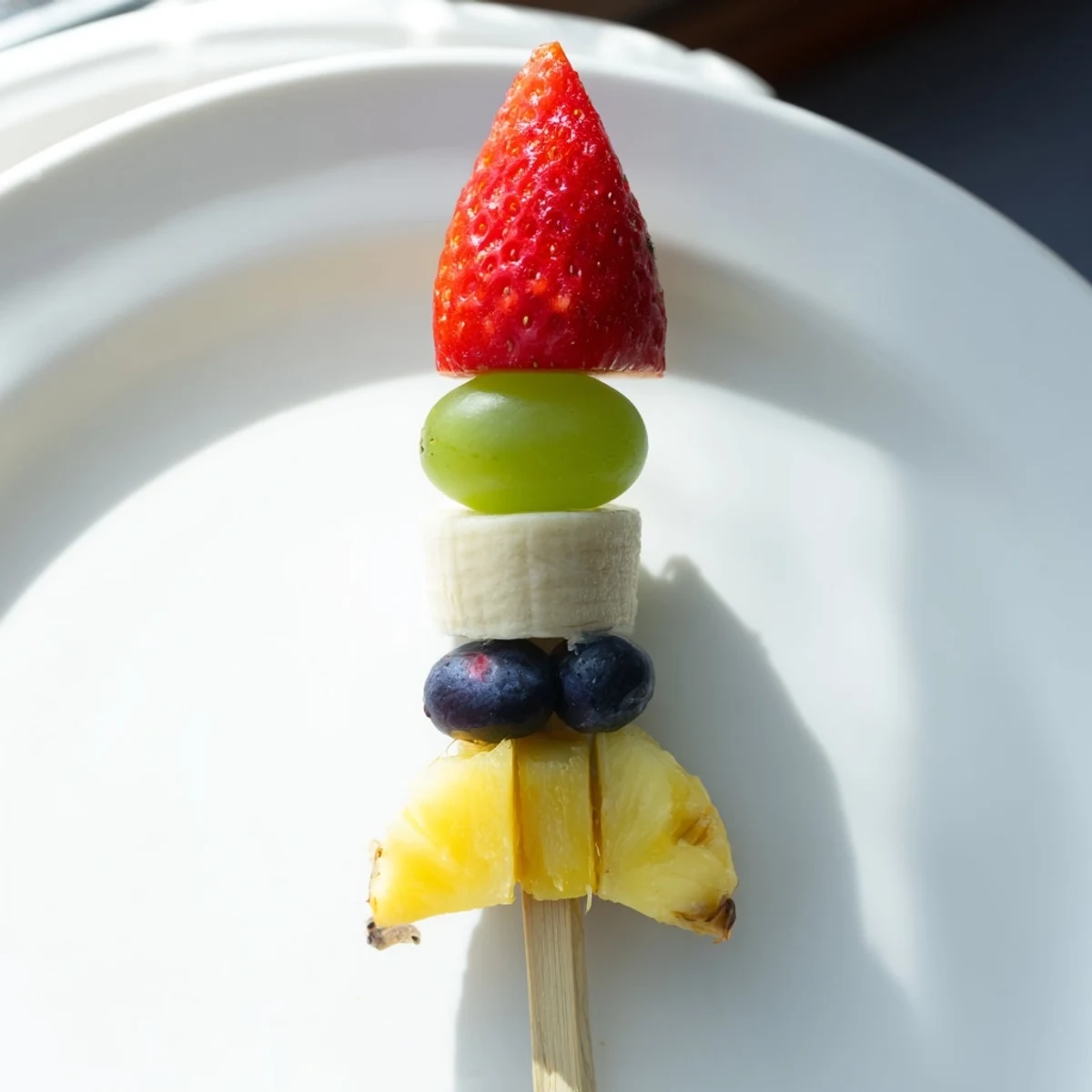 Bright red strawberry tops a Rocket Ship Fruit Skewer, ready for a kid's healthy snack.
