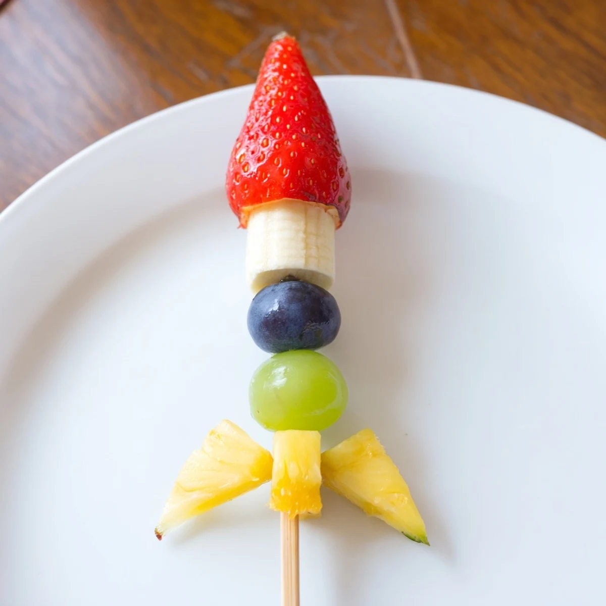 Fresh Pineapple flames burst beneath grapes and banana slices in this Rocket Ship Fruit Skewer.