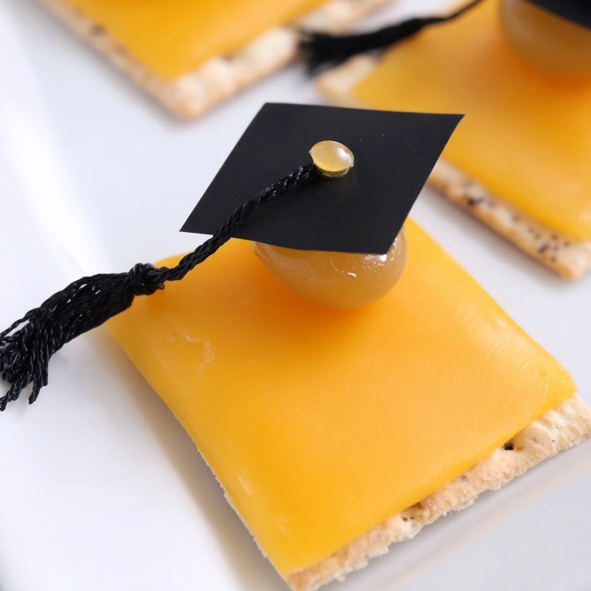 Graduation Cap Snacks: cheese-topped crackers with licorice tassels, ready for festive parties.