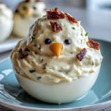 Adorable deviled egg chicks decorated with carrot beaks and black peppercorn eyes, perfect for Easter brunch.