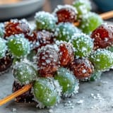Frozen grape skewers coated in zesty lime sugar, perfect for a refreshing summer snack.  