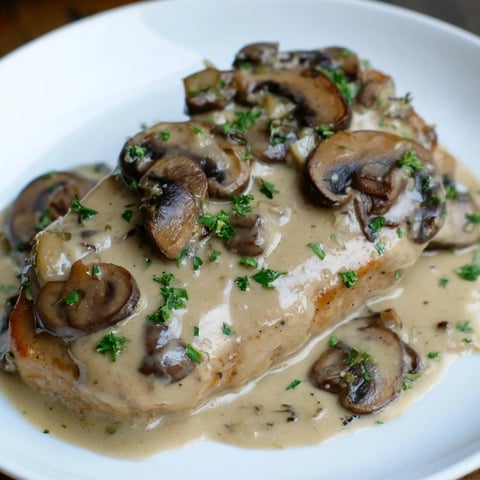 Close-up shot shows juicy stove top pork chops swimming in creamy mushroom sauce.