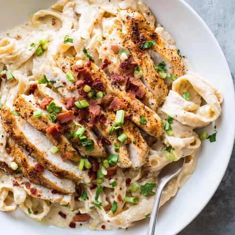 Creamy parmesan sauce blankets the Southern Style Creamy Parmesan Chicken Pasta, topped with fresh herbs and crumbled bacon.