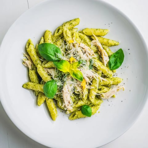 A beautiful bowl of 10-Minute Pesto Pasta with Chicken, garnished with fresh basil and Parmesan.