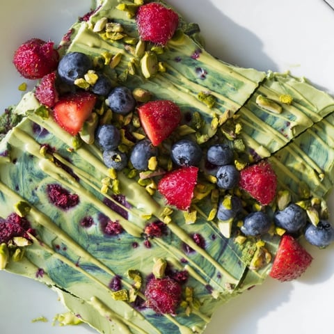 A close-up of vibrant Frozen Yogurt Bark, swirled with matcha and berry purees, ready to eat.