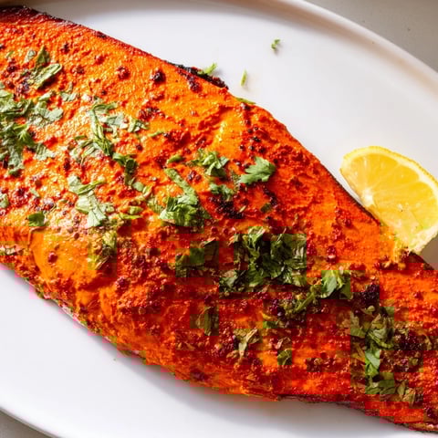 Fragrant Indian Tikka Salmon, baked to flaky perfection, garnished with fresh cilantro and lemon.