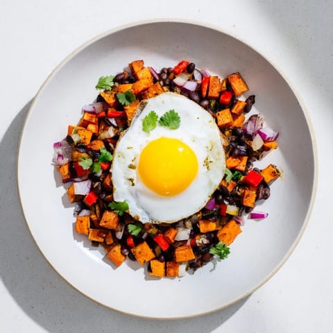 Vibrant sweet potato & black bean breakfast hash topped with perfectly cooked sunny-side-up eggs.