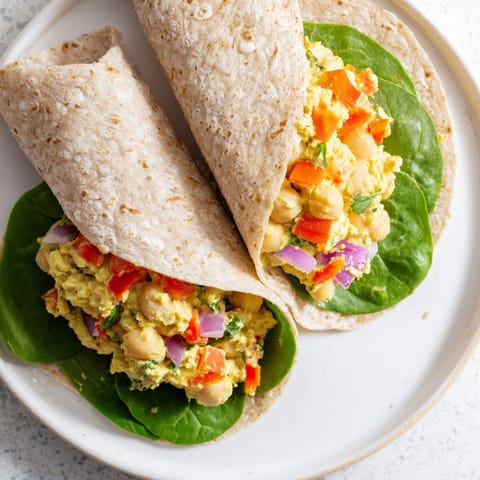 Enjoy a delicious plated chickpea salad wrap, filled with colorful vegetables and seasoned just right.