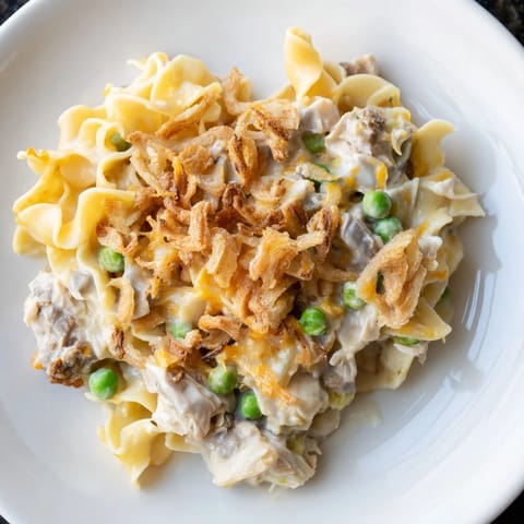 A close-up shot of a bubbling creamy tuna noodle casserole with a crispy onion topping.
