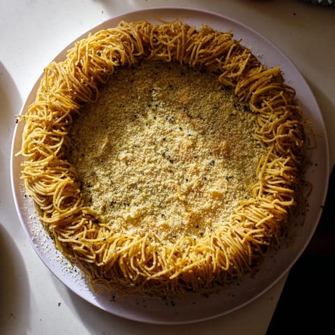A rustic slice reveals the cheesy, peppered layers of this Cacio e Pepe Pasta Pie recipe.