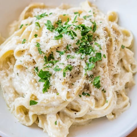 A bowl of fresh Cottage Cheese Alfredo Sauce, garnished with parsley, ready for a satisfying Italian meal.