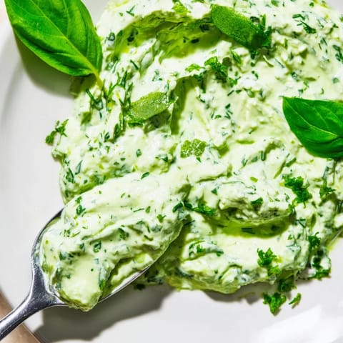 A bowl of creamy Green Goddess Salad Dip served with crunchy carrots, cucumbers, and vibrant peppers.