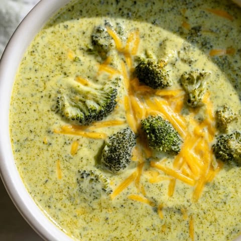 Hot Broccoli Cheddar Soup steams gently beside crusty bread, perfect for a cozy American dinner.