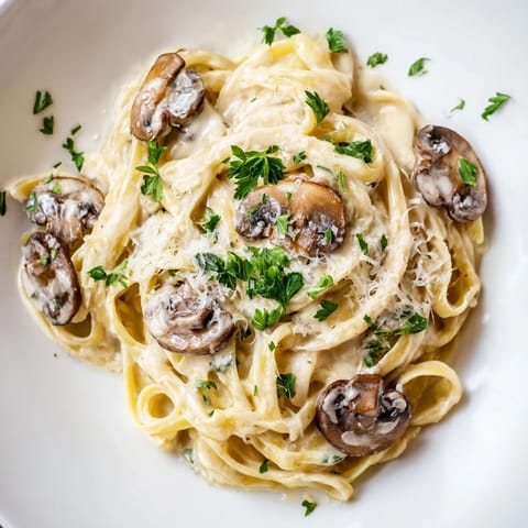 Creamy Mushroom Alfredo pasta twirled on a fork, showcasing sautéed mushrooms and a rich, velvety parmesan sauce.