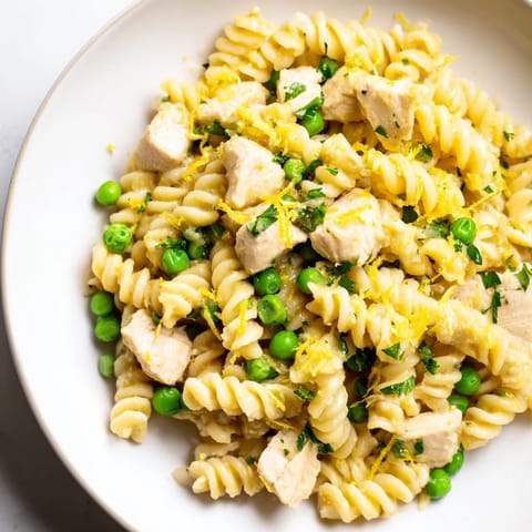 This hearty Garlic Butter Chicken & Pea Pasta is plated with a light sprinkle of Parmesan, ready for a family dinner.