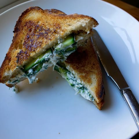 A close-up view of the crispy sourdough exterior and vibrant whipped feta filling in this easy Whipped Feta Spring Grilled Cheese.