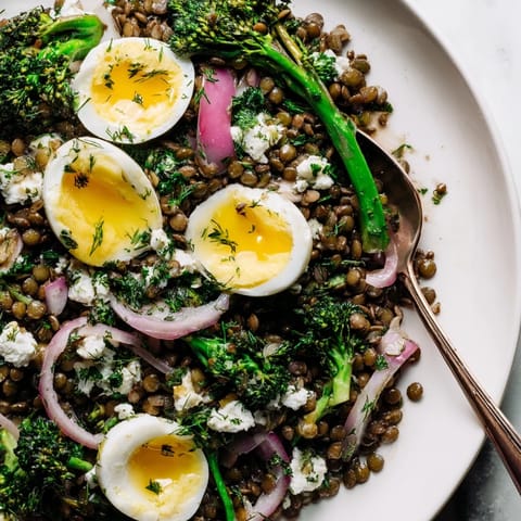 Hearty French lentil salad featuring tender broccolini, jammy eggs, and a tangy Dijon vinaigrette, ready to serve for a nutritious meal.