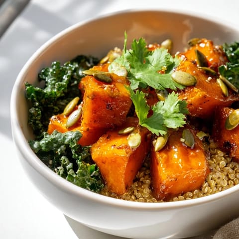 A warm, sweet and spicy red kuri squash bowl garnished with lime wedges and served over fluffy quinoa.