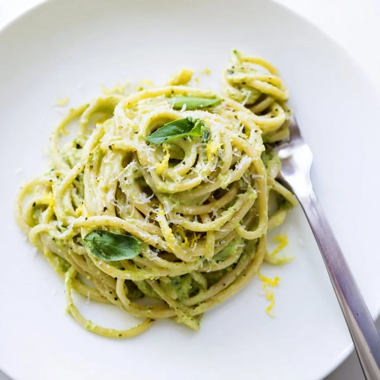 Enjoy a bowl of warm, creamy Creamy Avocado Pasta, garnished with fresh herbs and lemon zest.