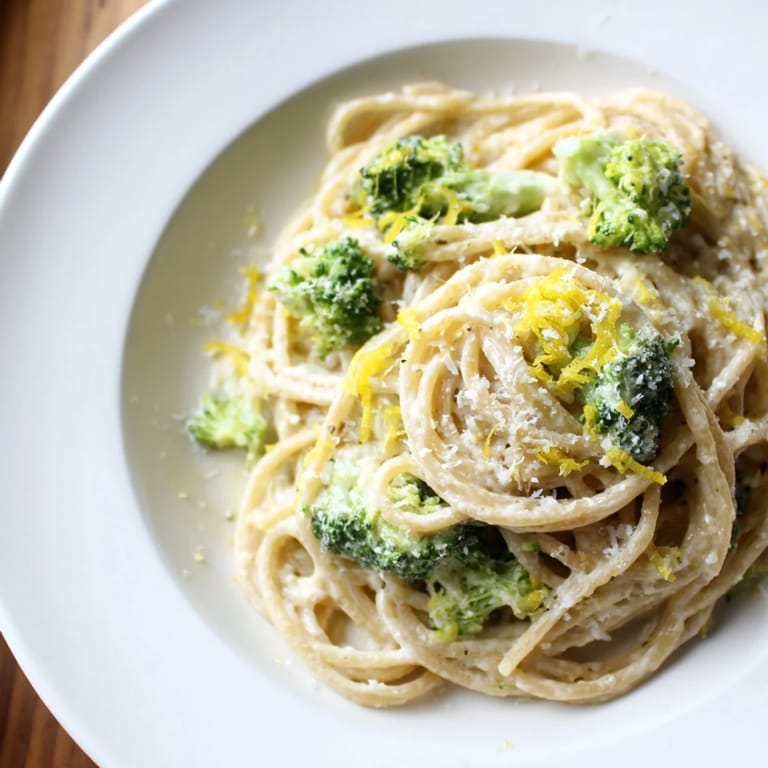 Close-up on a vibrant plate of one-pot lemon broccoli pasta with fresh basil and a lemon wedge.