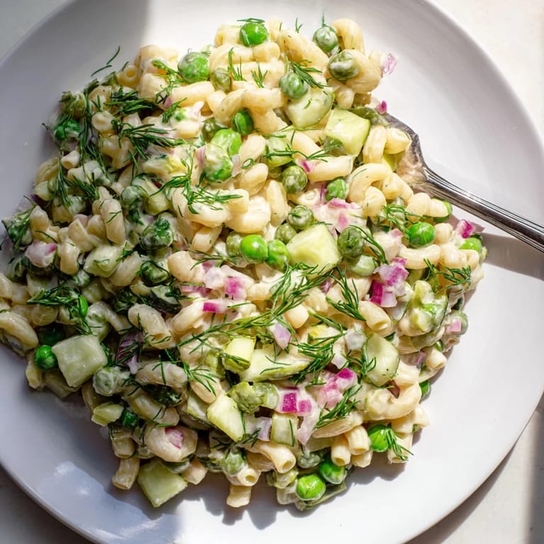 Overhead view of vegetarian creamy dill pickle pasta salad, rich dressing coating pasta, celery, and red onion for a perfect picnic side dish.