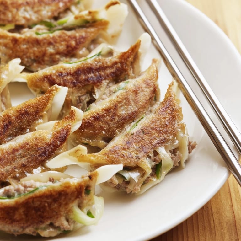 Pan-fried smashed gyozas with crispy edges and a tender pork and cabbage filling on a plate.  