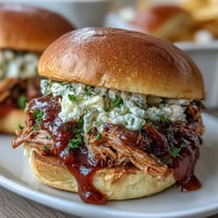 Slow cooker pulled pork sliders topped with tangy barbecue sauce and creamy coleslaw, perfect for baby shower parties and casual gatherings.  