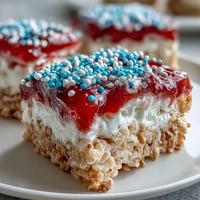 Layered red, white, and blue Rice Krispies treats with vibrant colors and sprinkles for a festive 4th of July dessert.  