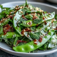 Crisp snap pea and radish salad with fresh mint, parsley, and creamy tahini dressing, perfect for a light spring meal.  